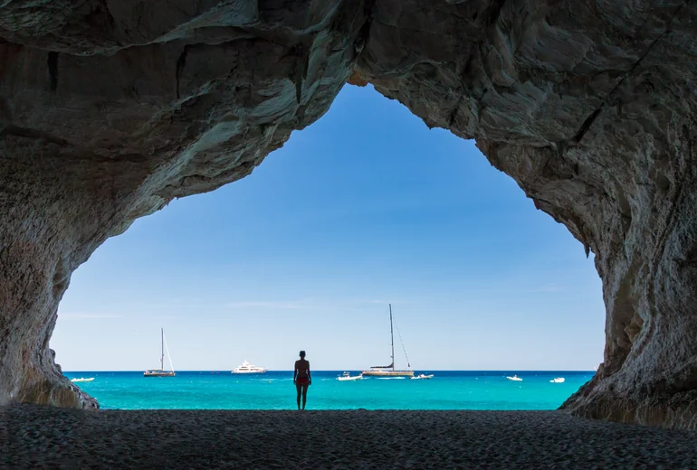 Italian Mediterranean coastline with rocky cliffs and a charter sailing yacht offshore