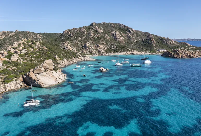 Aerial of a granite cove anchorage with a catamaran and yachts in the La Maddalena archipelago