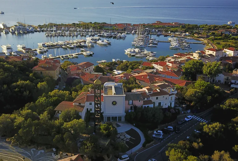 Aerial of Porto Rotondo village, church tower and marina at golden evening light
