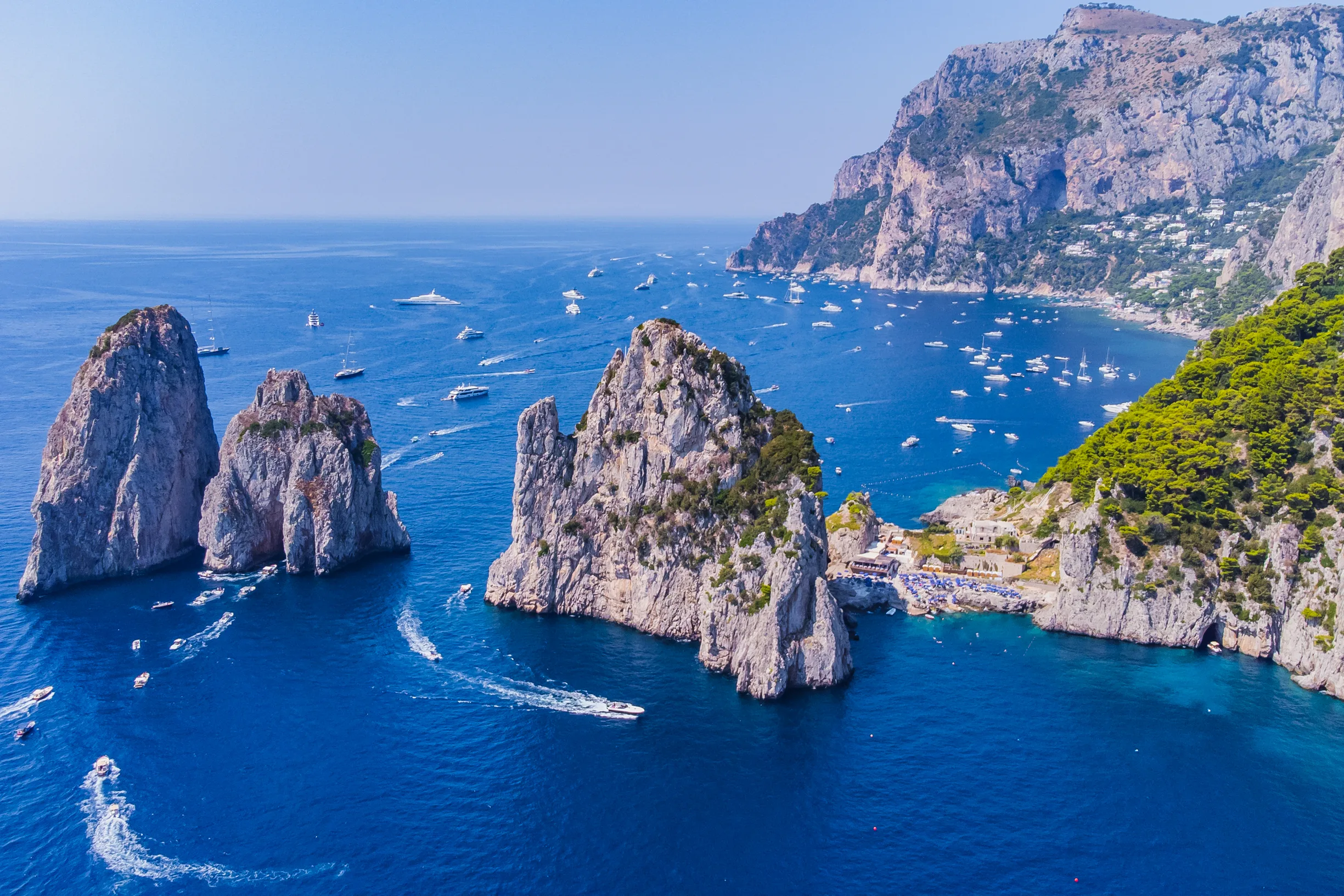 Aerial of Capri Faraglioni sea stacks surrounded by yachts and boats