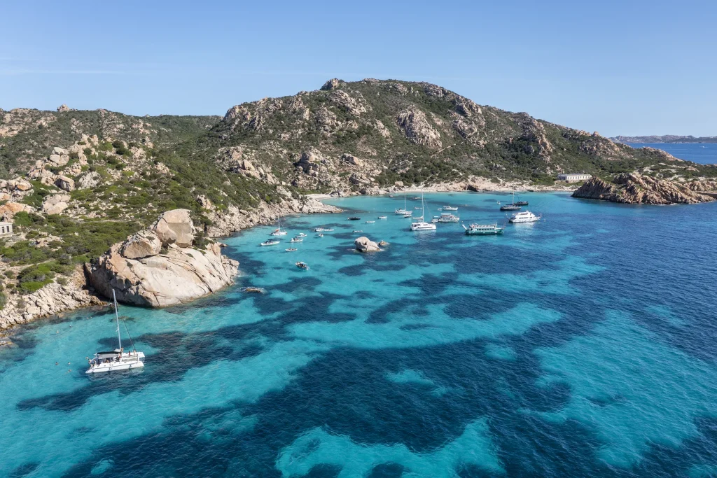 Aerial of granite cove anchorage with catamaran and yachts, La Maddalena archipelago
