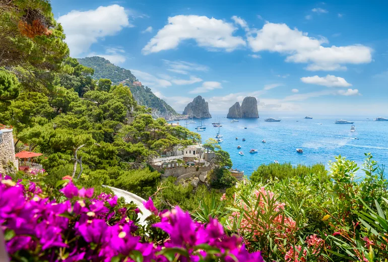 Capri Faraglioni rocks framed by bougainvillea with boats at anchor