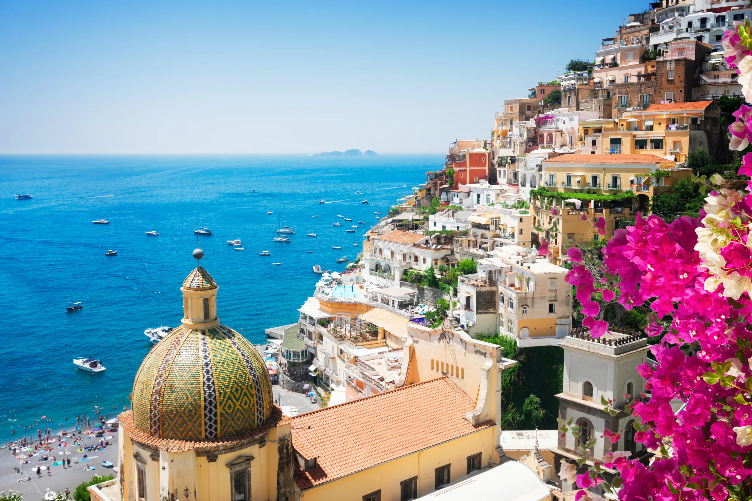 Positano church dome and cliffside houses with pink bougainvillea and boats