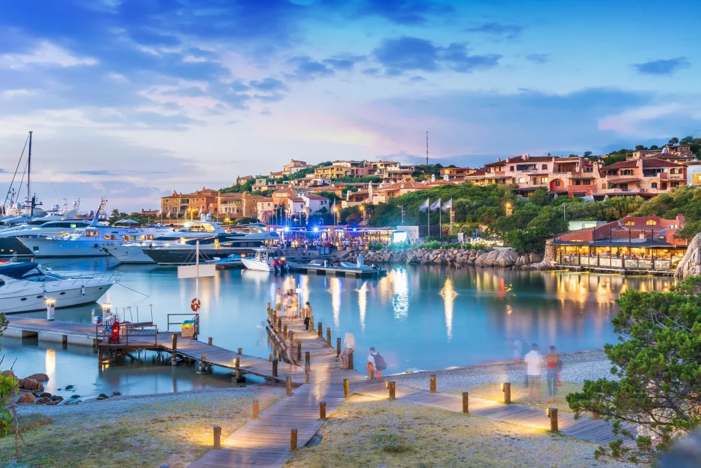 Porto Cervo harbor village at dusk with illuminated houses and moored motoryachts