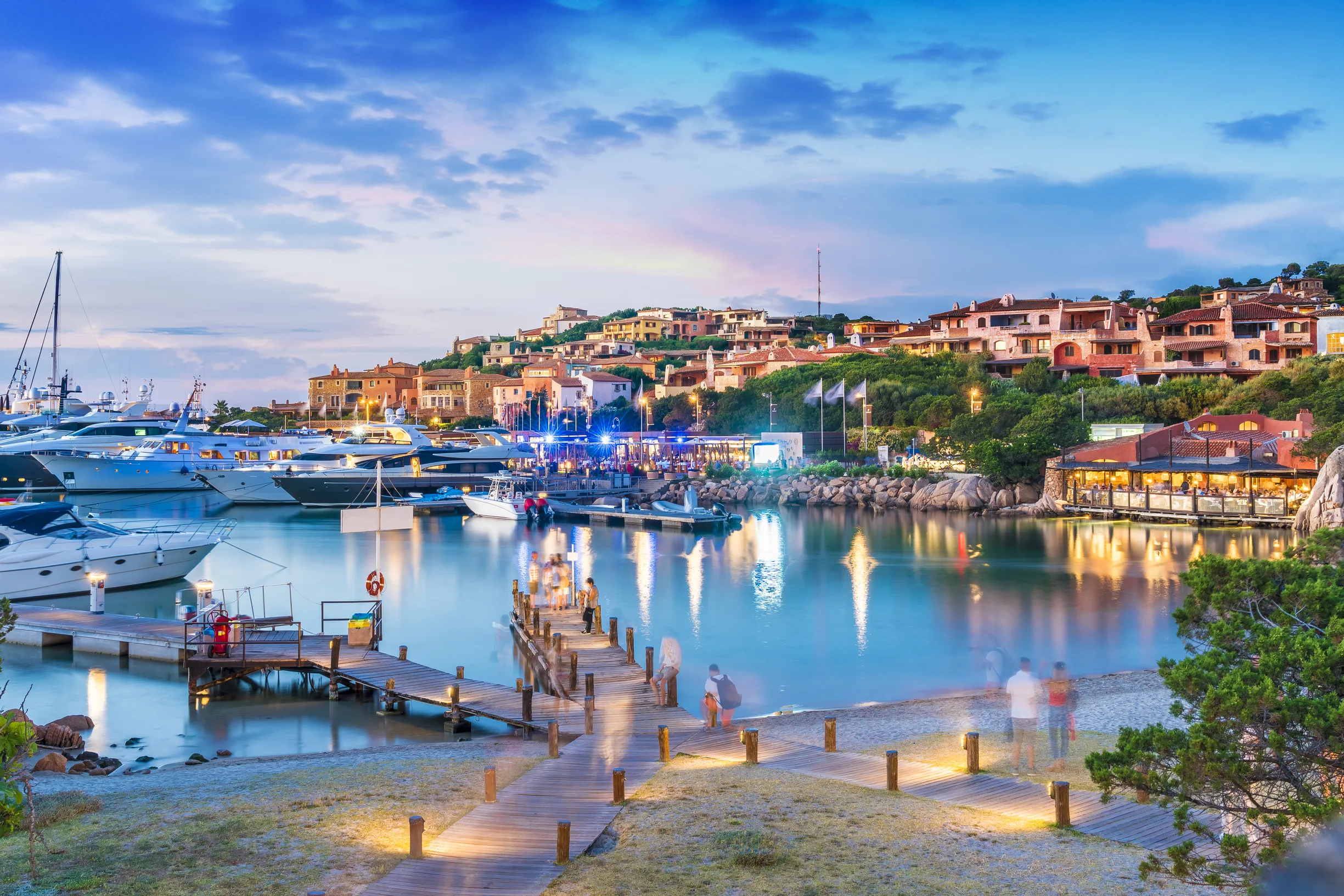 Porto Cervo harbor village at dusk with illuminated houses and moored motoryachts