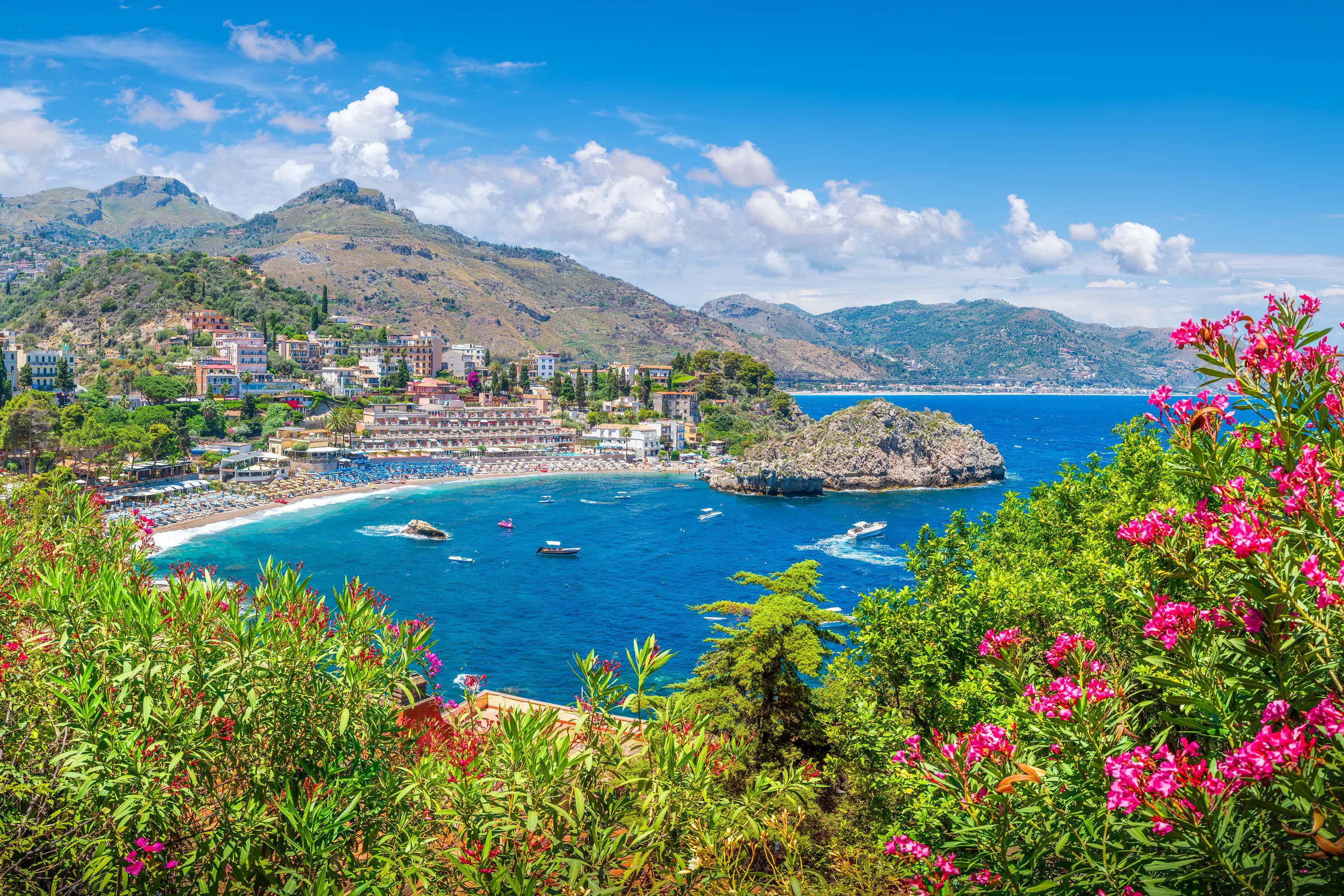 Flower-framed view of Taormina bay with beach resort and rocky islet