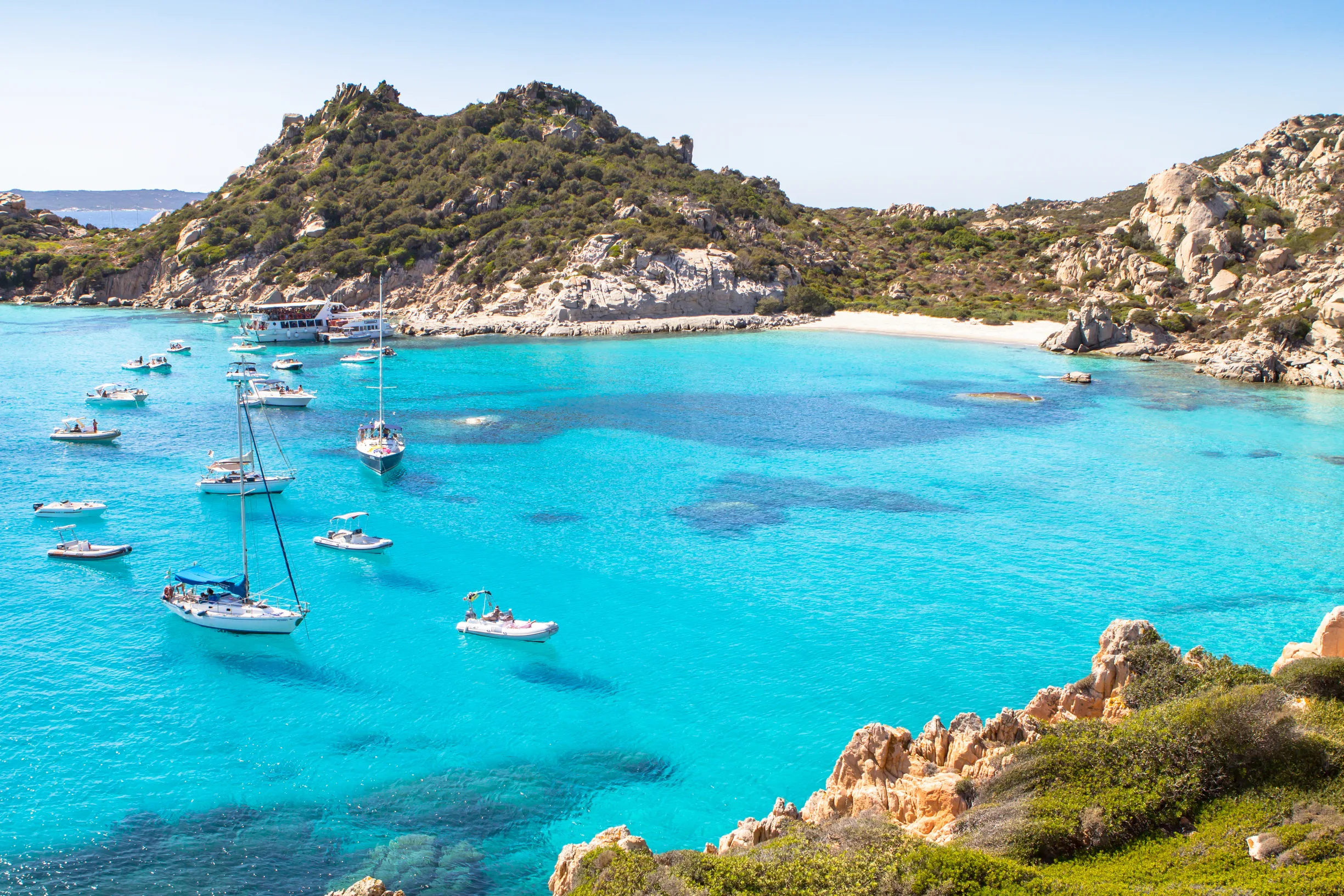 Sailboats anchored in shallow turquoise bay, La Maddalena archipelago, Sardinia