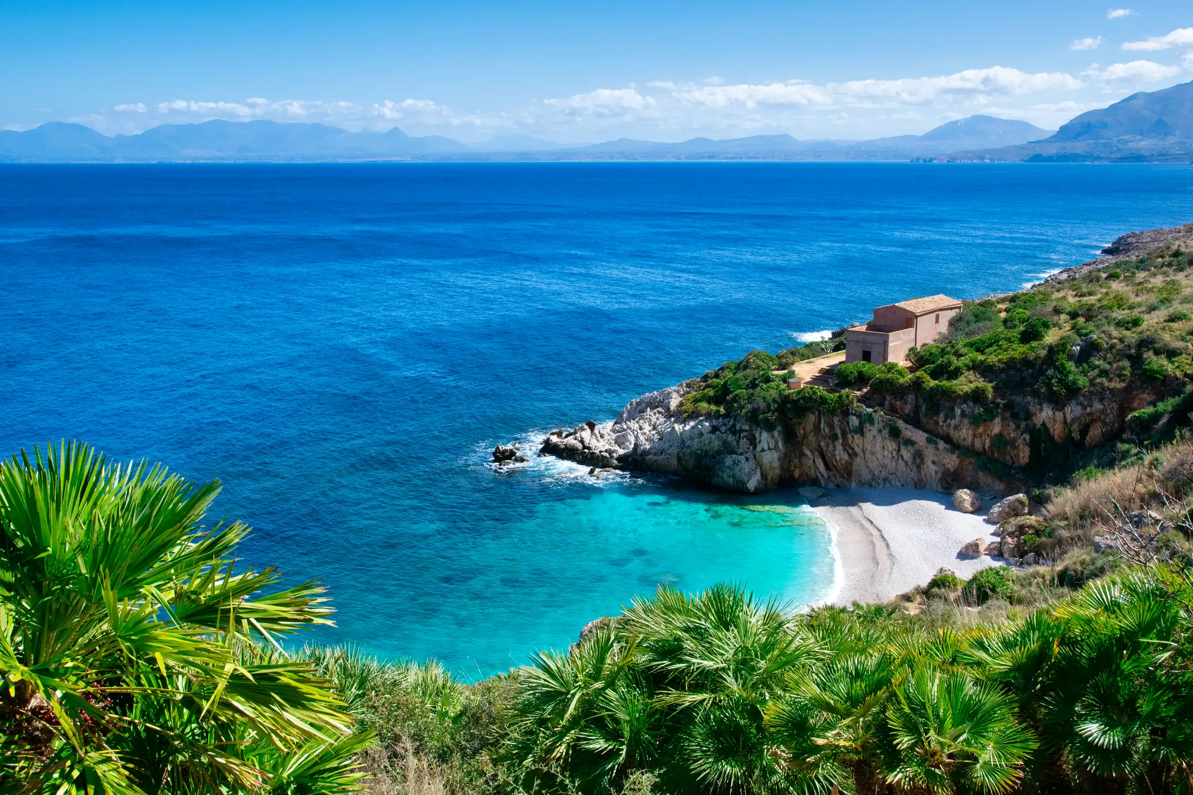 Secluded white pebble cove with palms in Zingaro Nature Reserve, Sicily