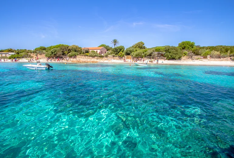 Shallow turquoise cove with clear water over pale sand and a sandy beach