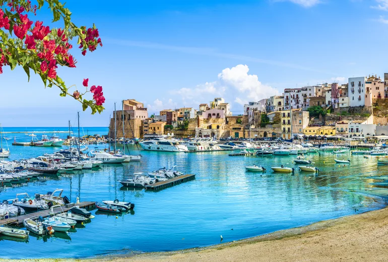 Small boats filling Castellammare del Golfo harbor below a castle, Sicily