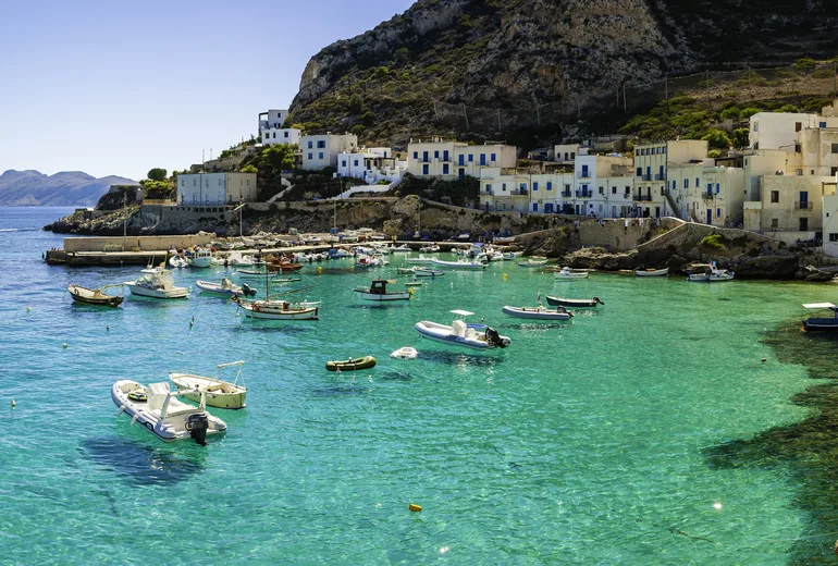 Small boats on clear turquoise water in a village harbor