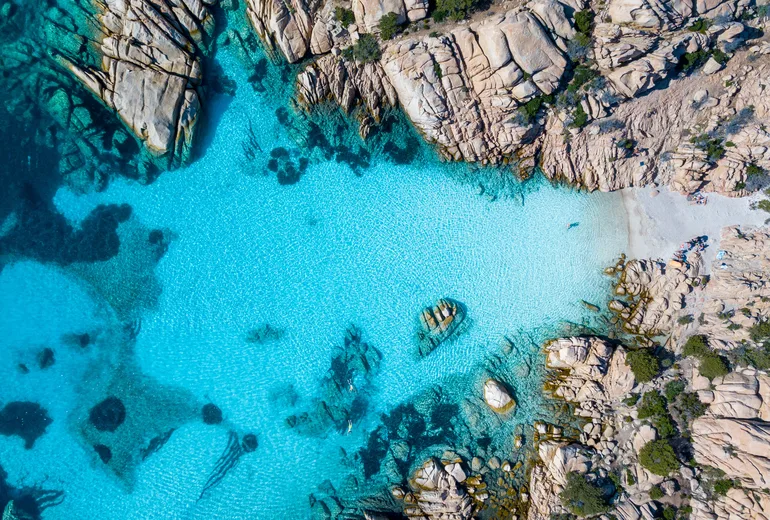 Top-down aerial of a turquoise cove between granite rocks on Caprera in Sardinia