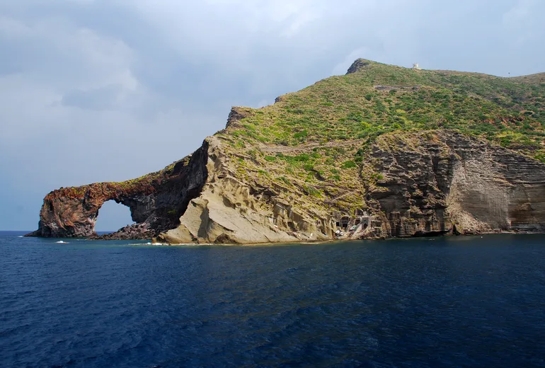 Volcanic headland with a natural rock arch on a Tyrrhenian island coastline